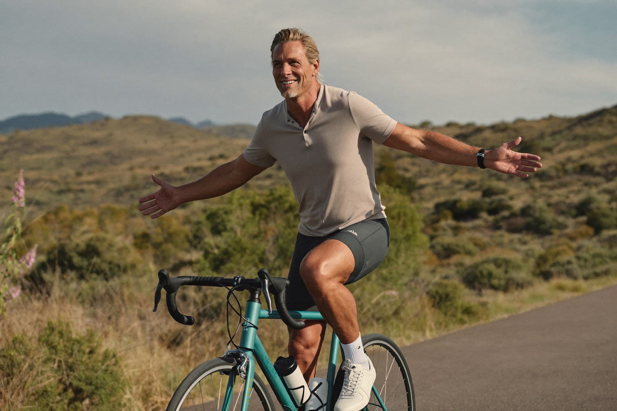 Man riding a road bike through the Colorado foothills, arms outstretched